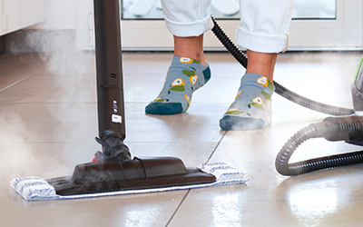L'immagine mostra una persone che pulisce con il vapore il pavimento